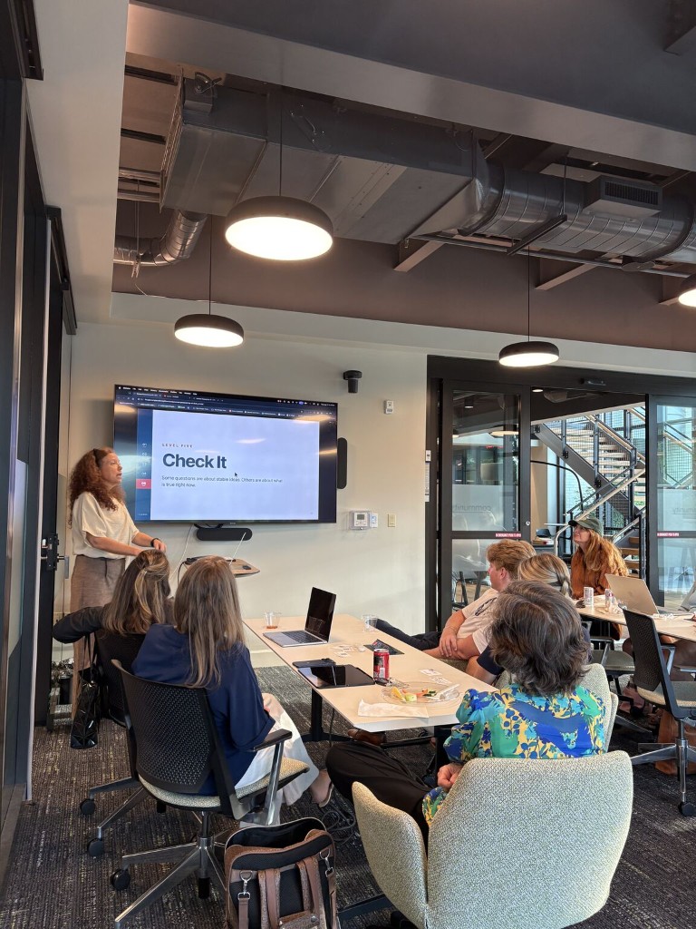 Laura Florey presenting to a seated audience at the Women Powered by AI meetup at Hatch in Fairhope